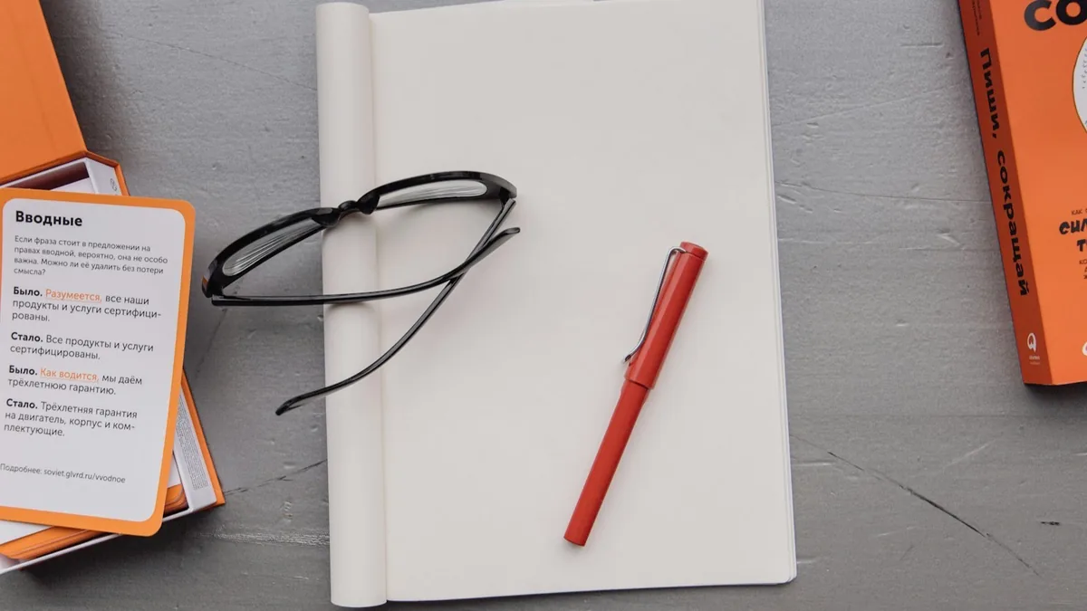 Reading glasses and a red pen on an edited manuscript